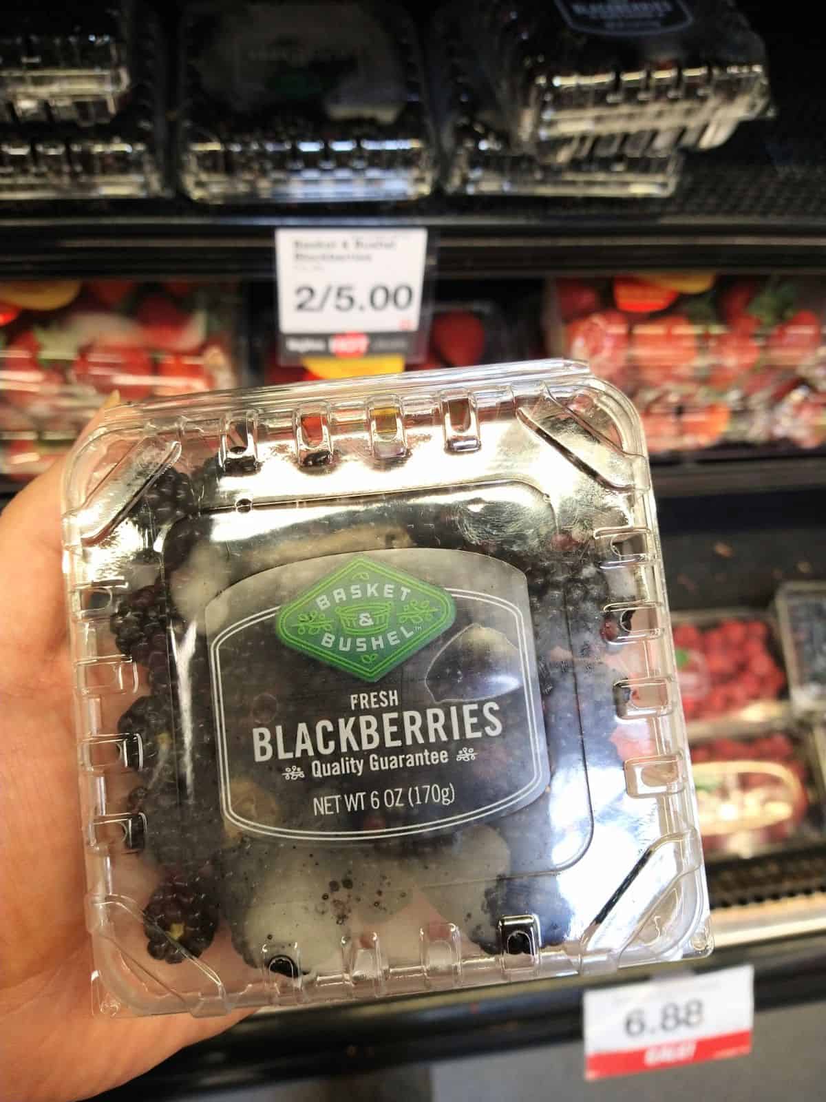 Holding up a 6 ounce package of Basket & Bushel Fresh blackberries at the grocery store.