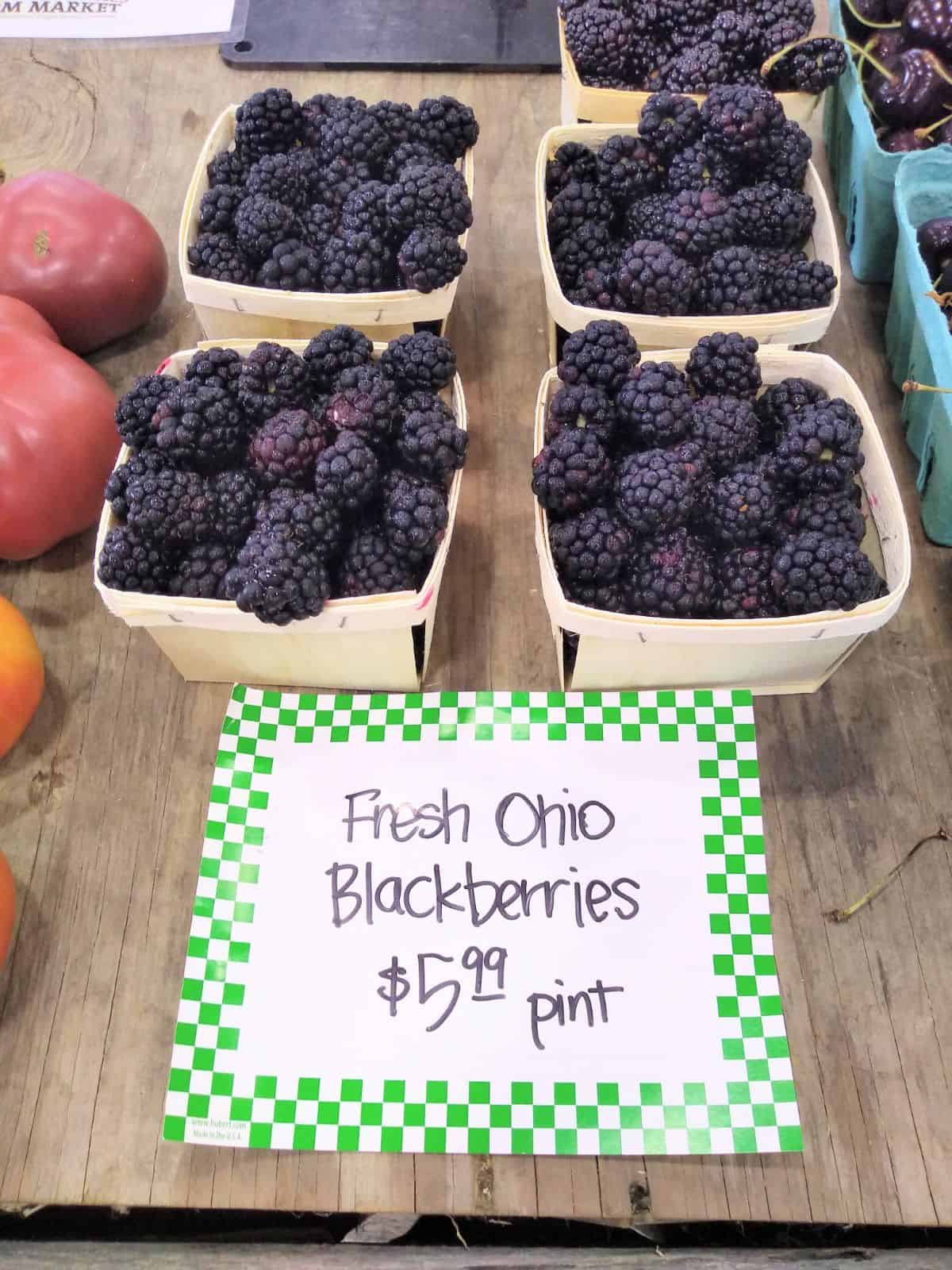 A table of pints of Fresh Ohio blackberries on a table at a farmer's market selling for $5.99 each.