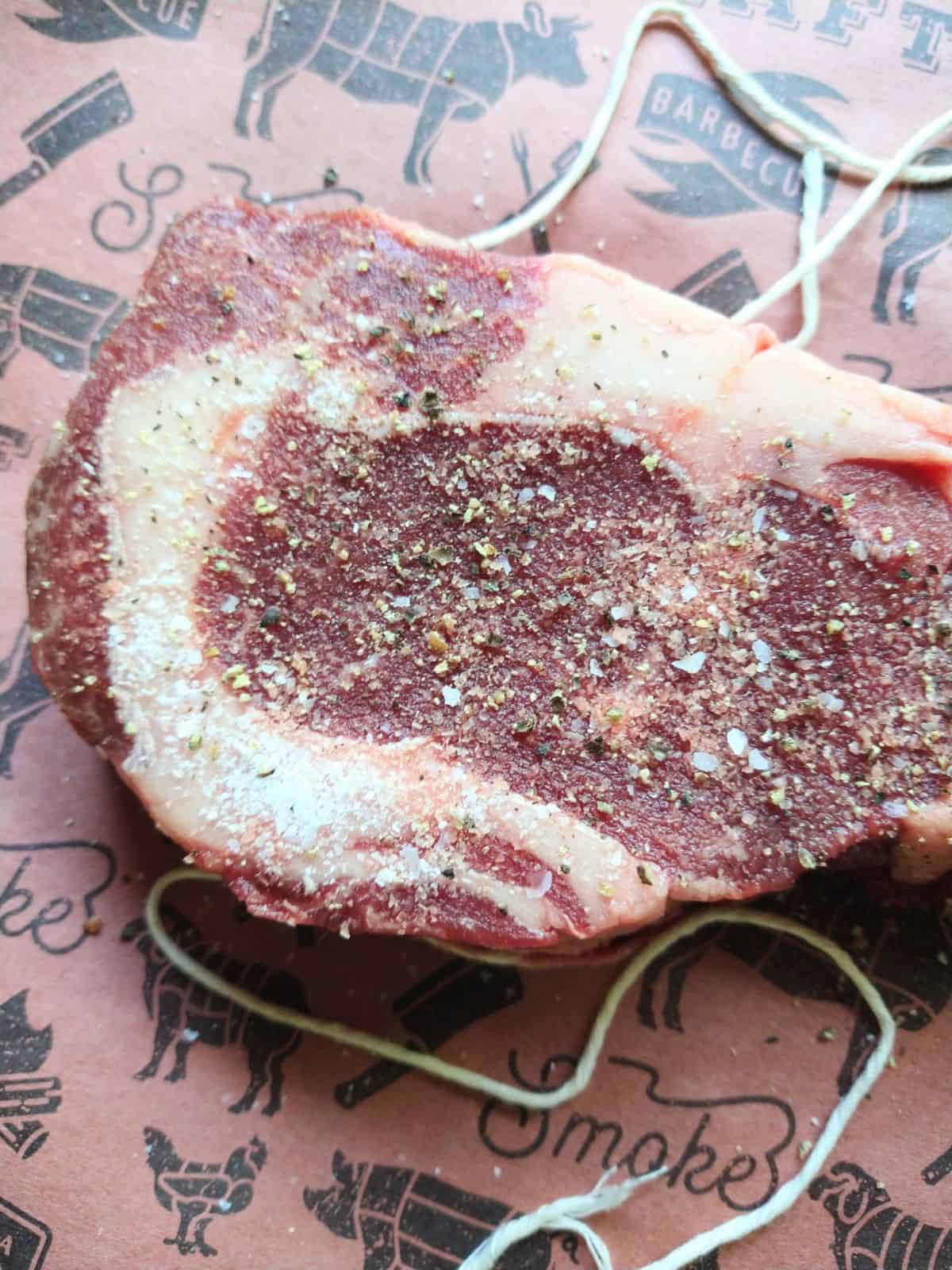Up close picture of Bison ribeye steak  has been seasoned with salt and pepper. 