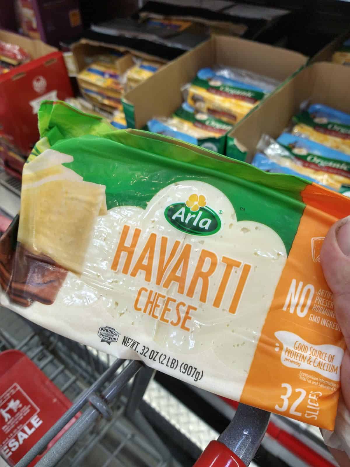 A package of Arla Havarti Cheese slices being held up.