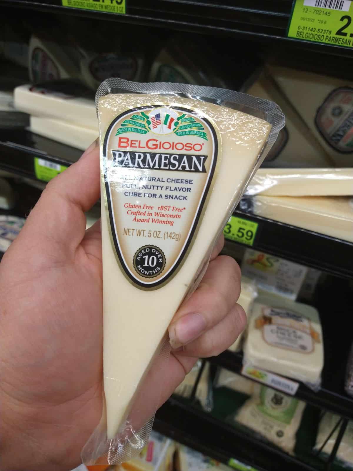 A wedge of BelGioIoso parmesan cheese is being held at the grocery store.