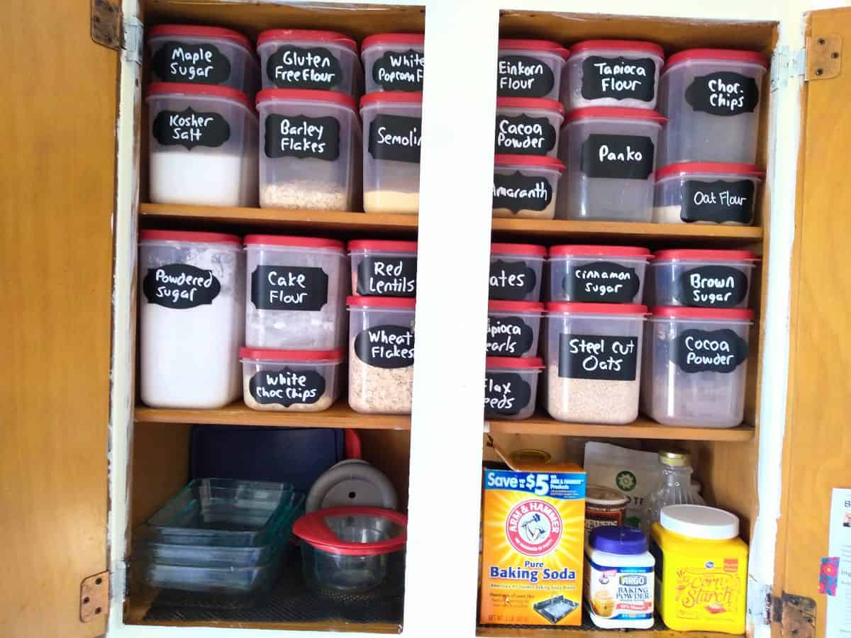 A pantry that is filled with Rubbermaid canister containers that have chalkboard sticks on them that have what's inside written on the sticker. 