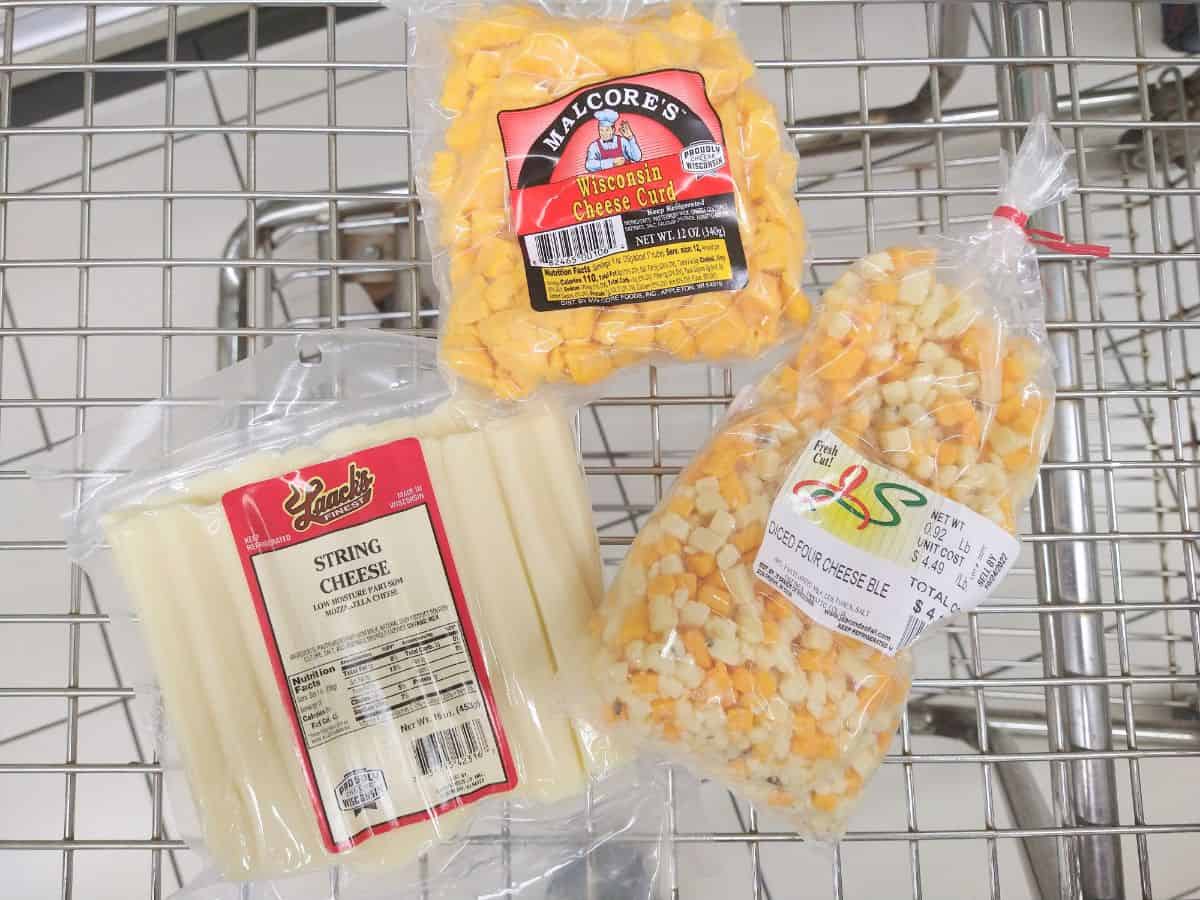 A metal shopping cart with Malcore's Wisconsin Cheese Curds, String chees, and a bag of diced cheese. 