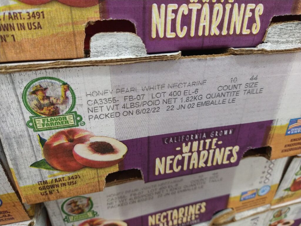 Boxes of Flavor Farmer California Grown White Nectarines stacked up at a Costco store.