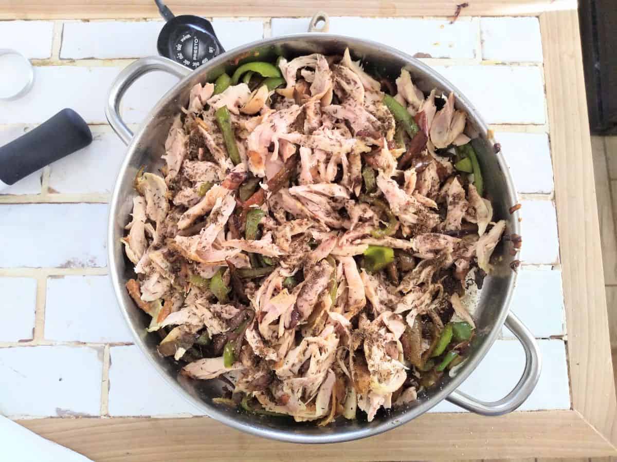 An electric skillet filled with chicken fajitas with green bell peppers.