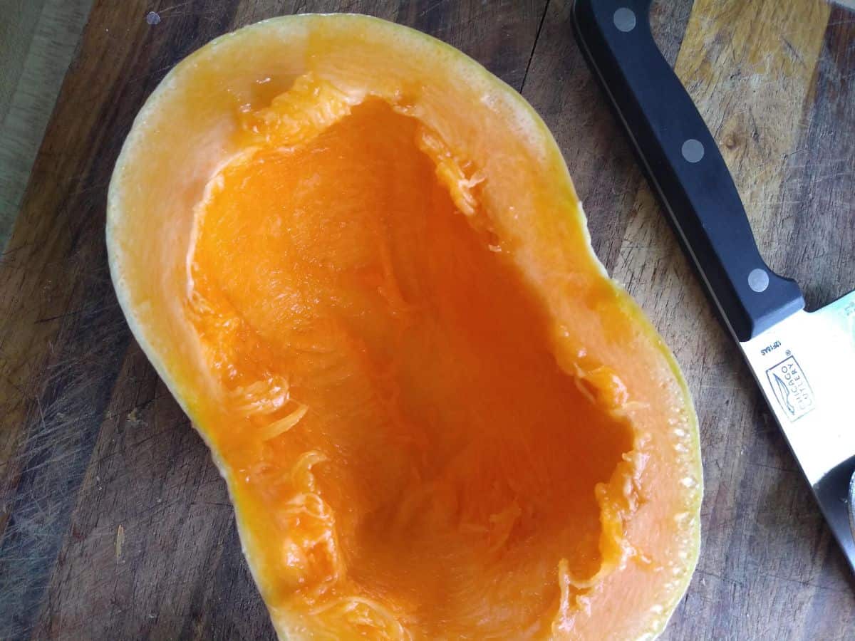 A Long Island cheese pumpkin cut in half showing the bright orange interior.