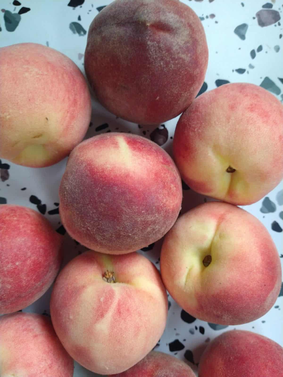 Whole White Lady White Peaches on a white table with spots.