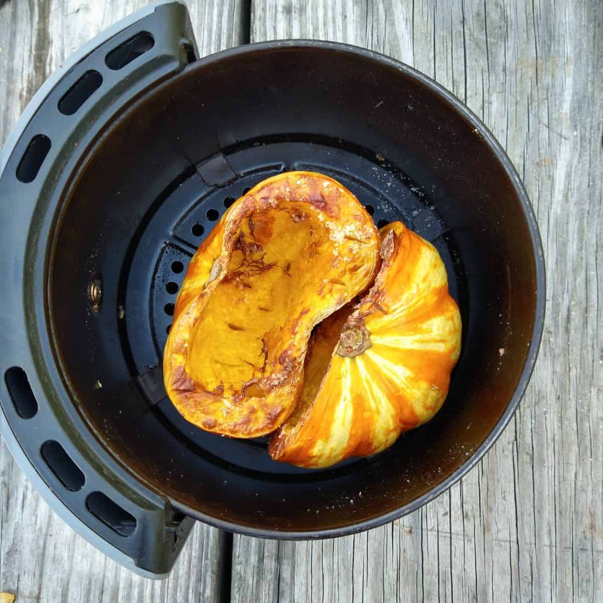 A Tiger Strip pumpkin cut in half that has been cooked in an air fryer. It is shown inside the basket. 