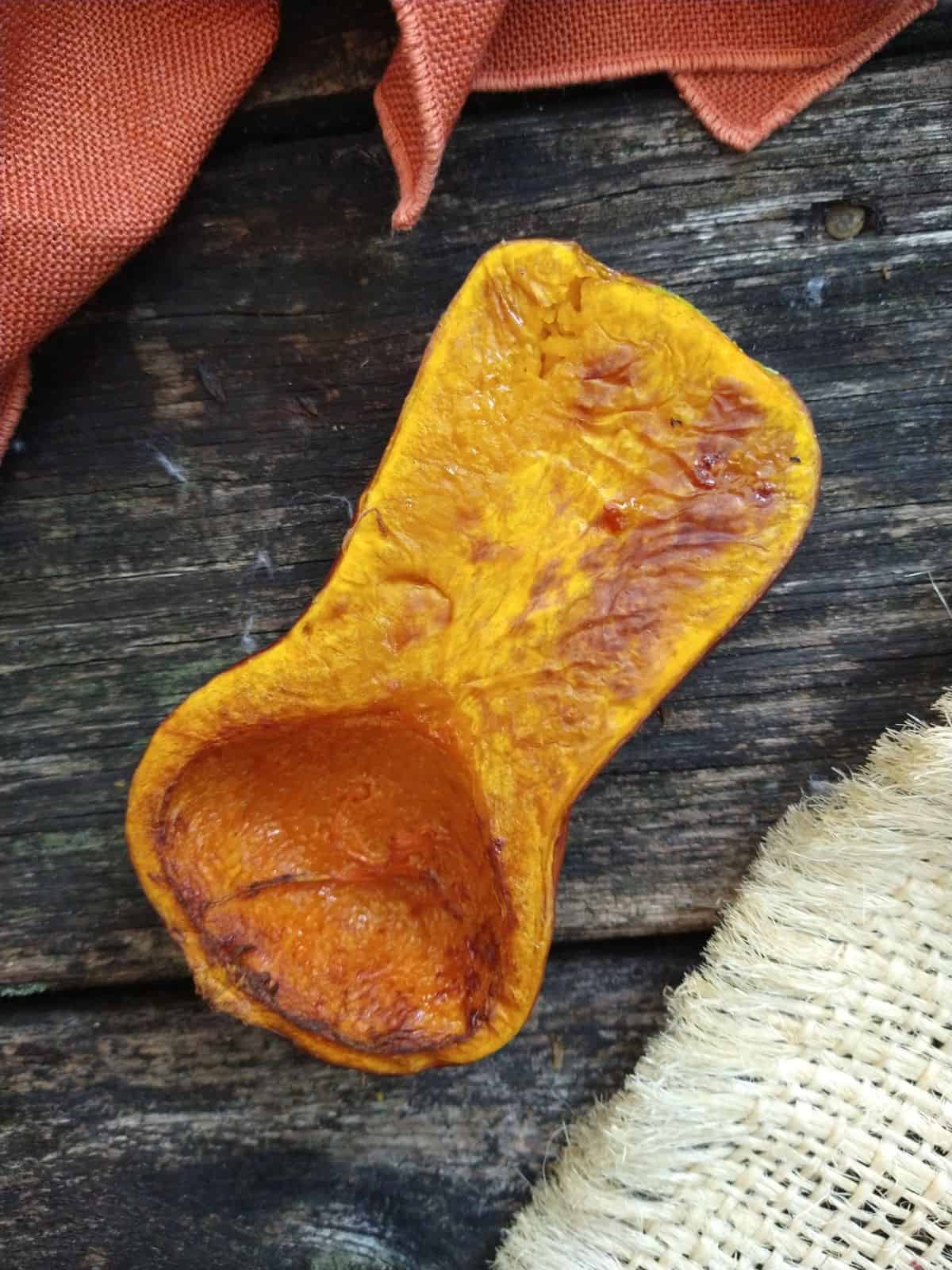 A browned half of a Honeynut squash sitting on a wood picnic table. 