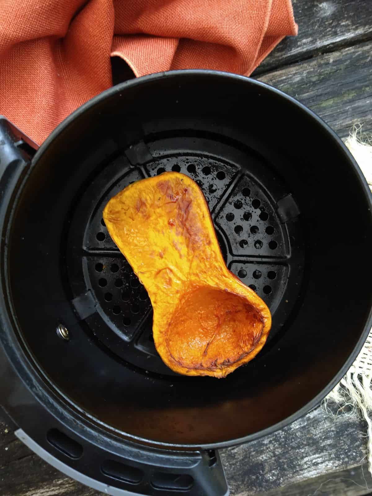 Honeynut squash in a black air fryer basket after it's been browned and cooked.