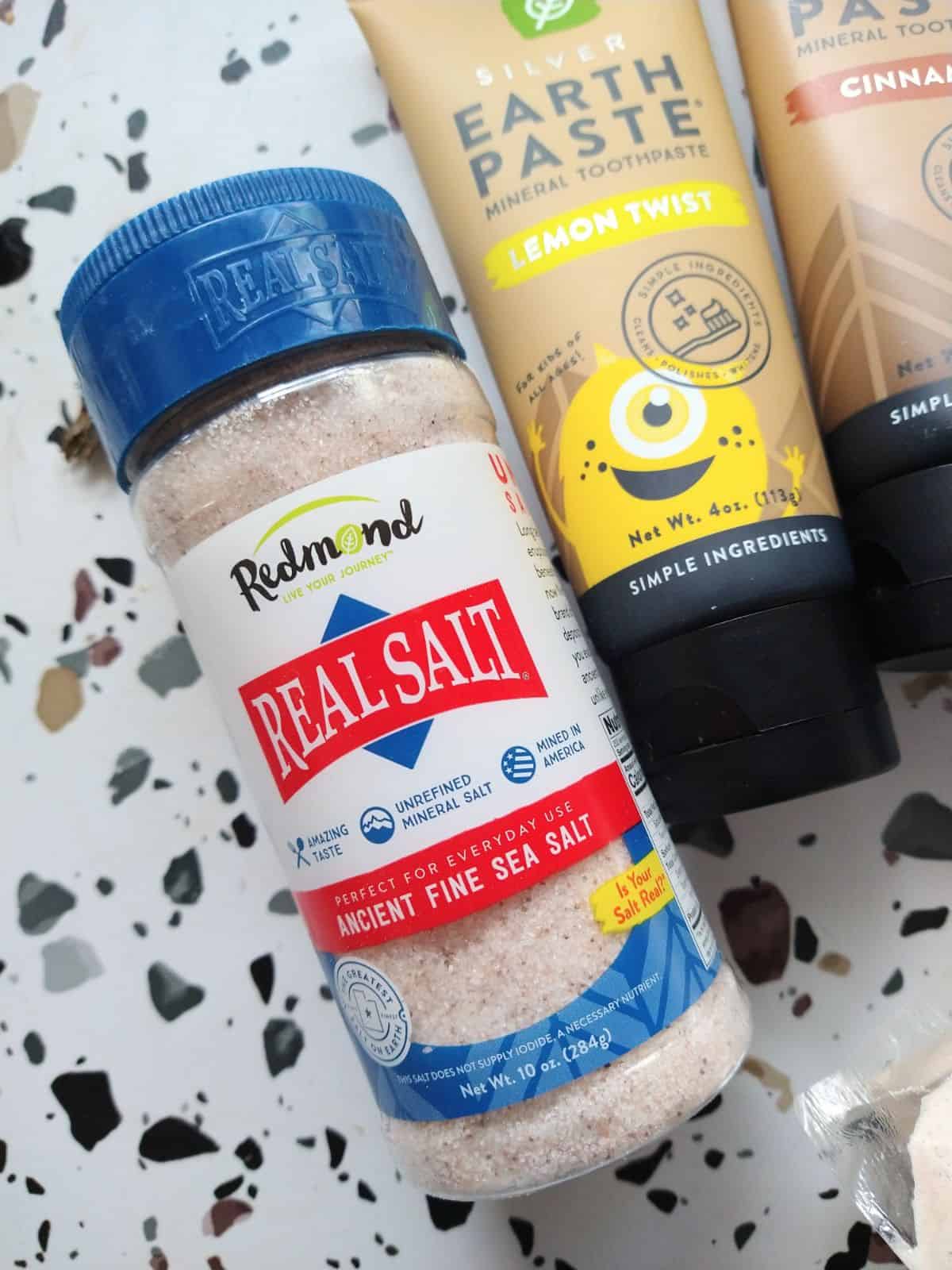 A shaker container with a blue lid of Redmond real Salt Ancient Fine Sea Salt. 