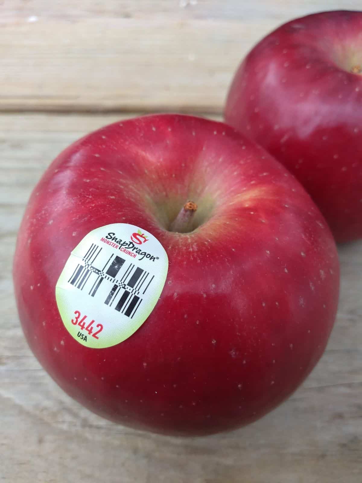SnapDragon apples sitting on a wood table with the  PLU sticker showing the front