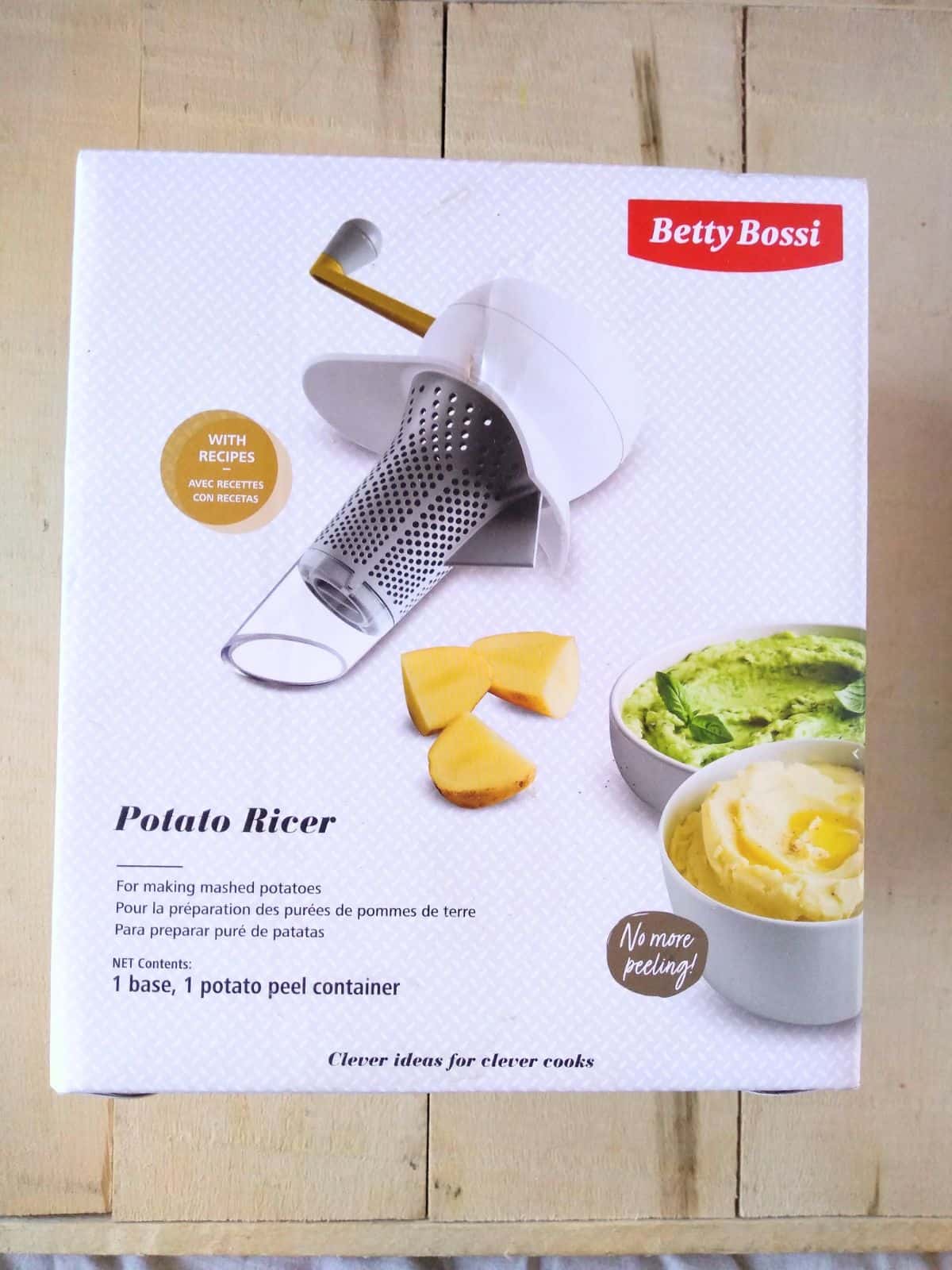 A Betty Bossi Potato Ricer inside the box it came in sitting on a wood board.