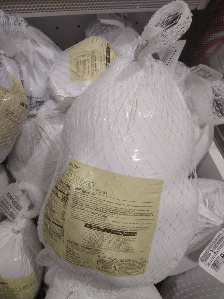 A display of Greenwise Young turkeys wrapped in white packaging with white netting. 