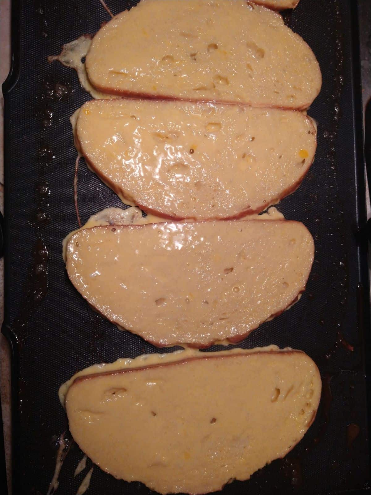 Slices of sourdough bread up on an electric griddle after being dipped in eggs and egg nog.