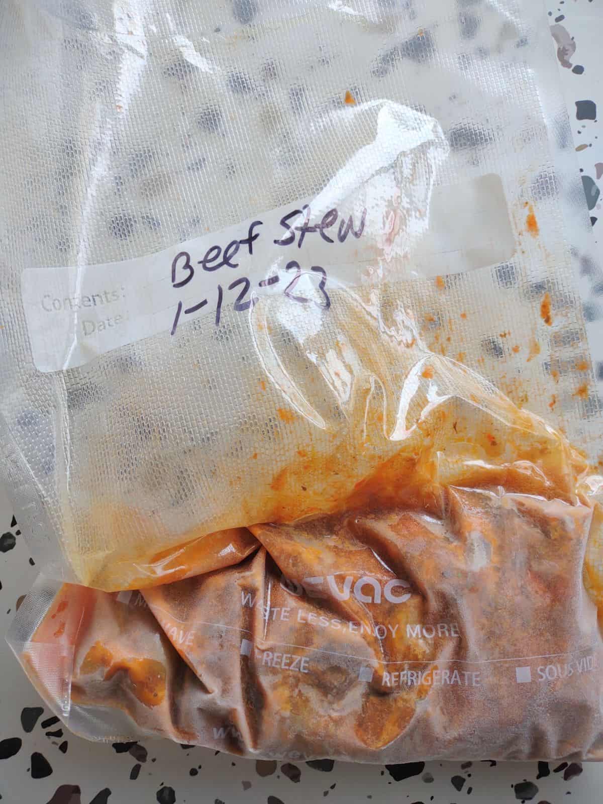 A vacuum sealed bag labeled beef stew with frozen stew inside.