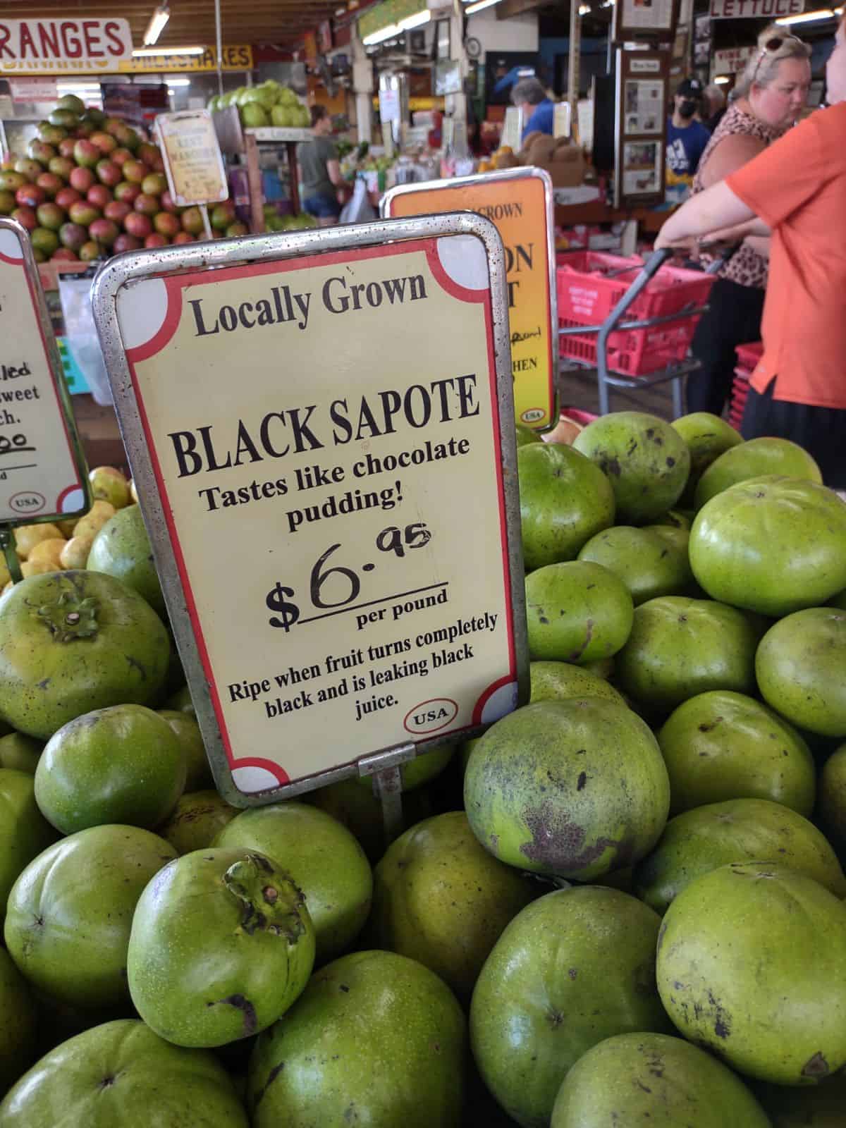 Locally grown black sapote on display at a produce market. 