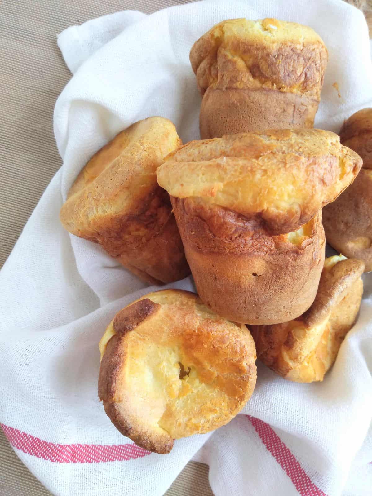 Several finished popover sitting on a white towel with a red stripe.