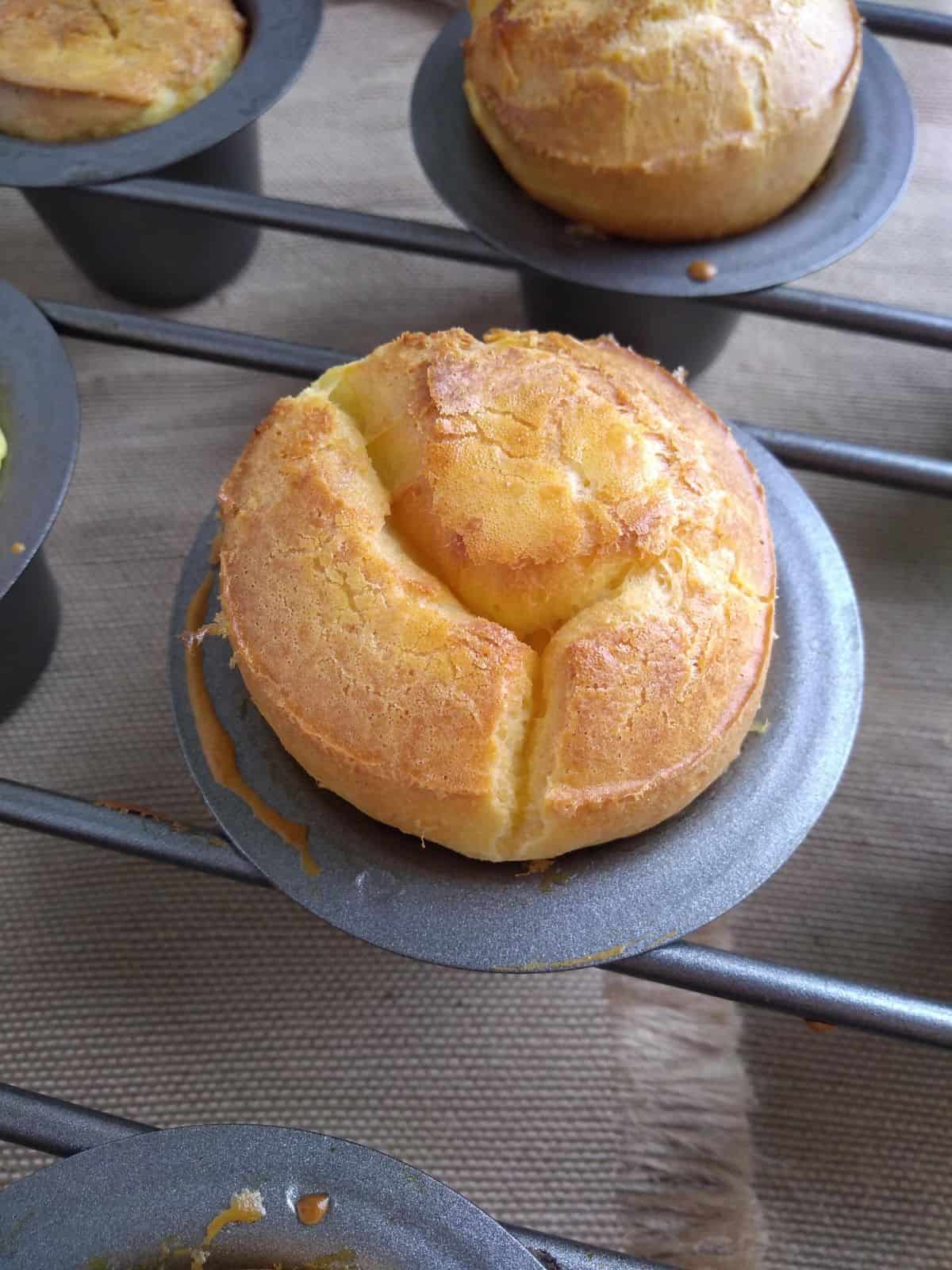 A close up of a crusty top of a popover still in a popover pan.