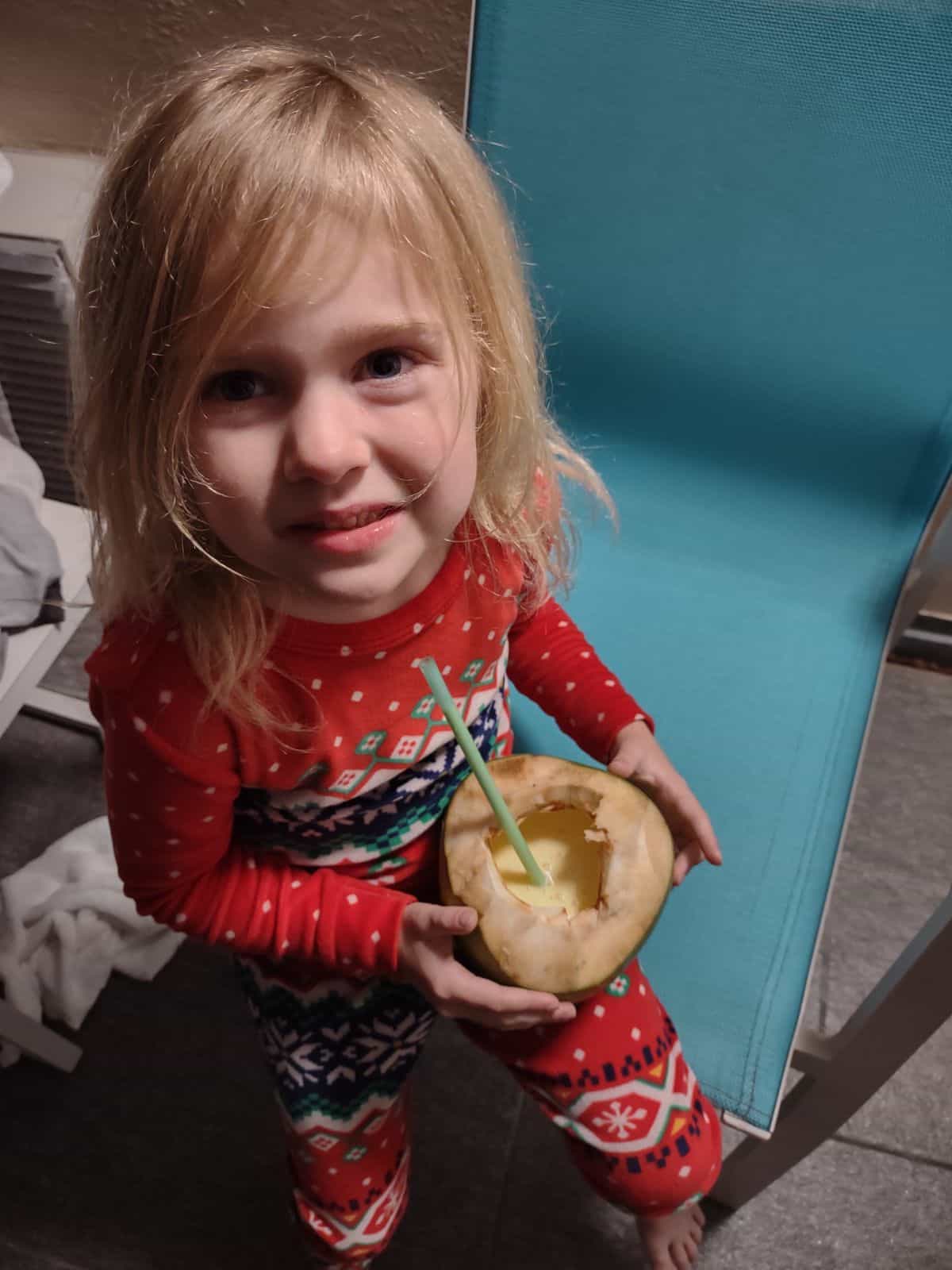 My youngest daughter holding a coconut that has been emptied and is filled a smoothie. 