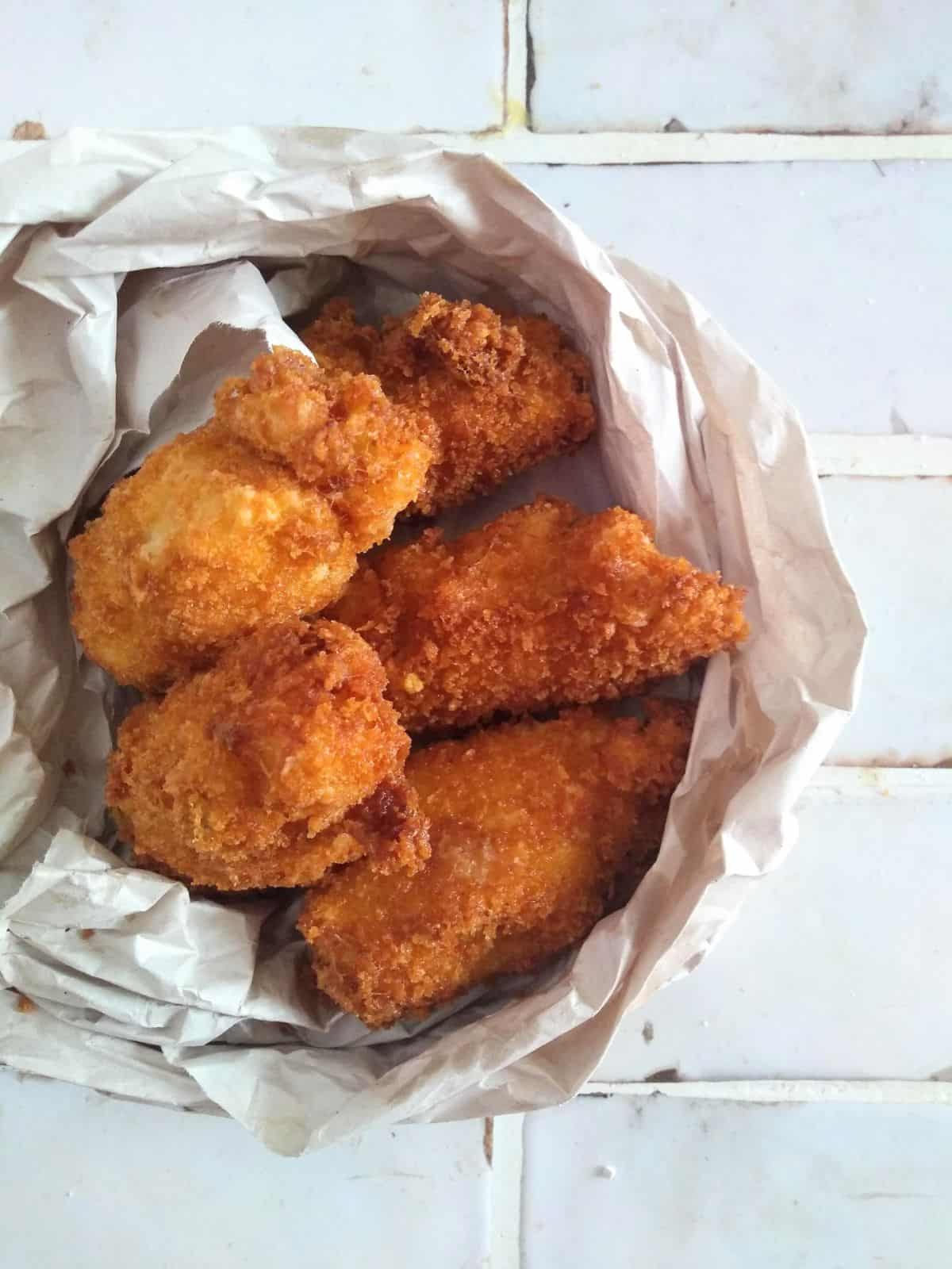 Alton Brown's fish sticks on a white tile counter wrapped in paper