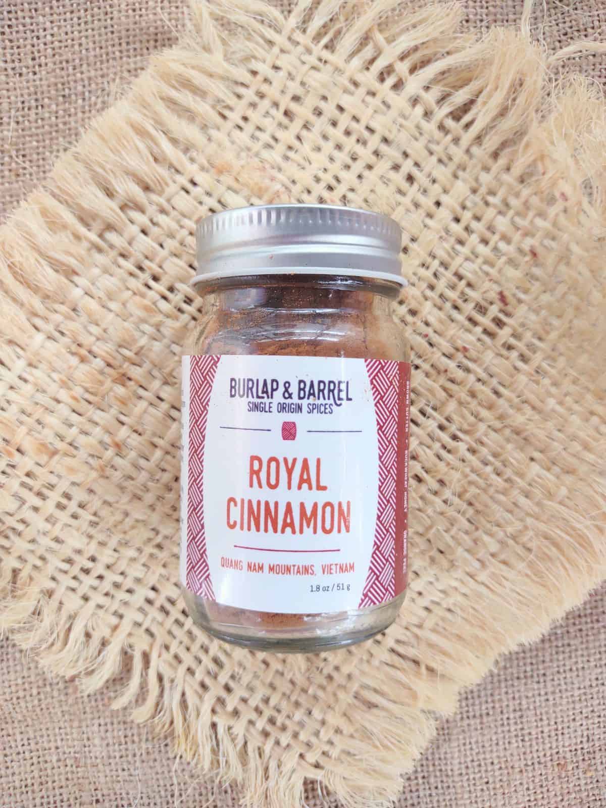 A glass jar of Burlap & Barrel Royal Cinnamon on a piece of burlap.