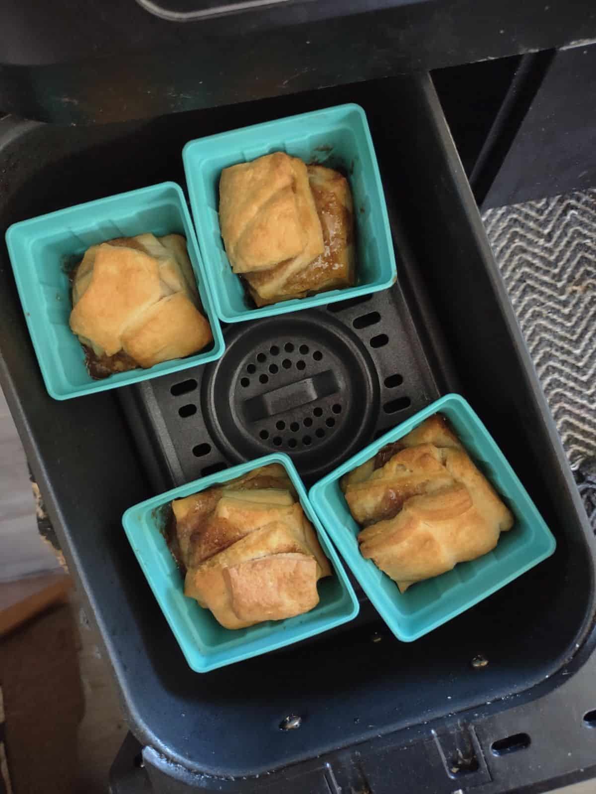 4 silicone baking cups filled with cooked dough in an air fryer basket