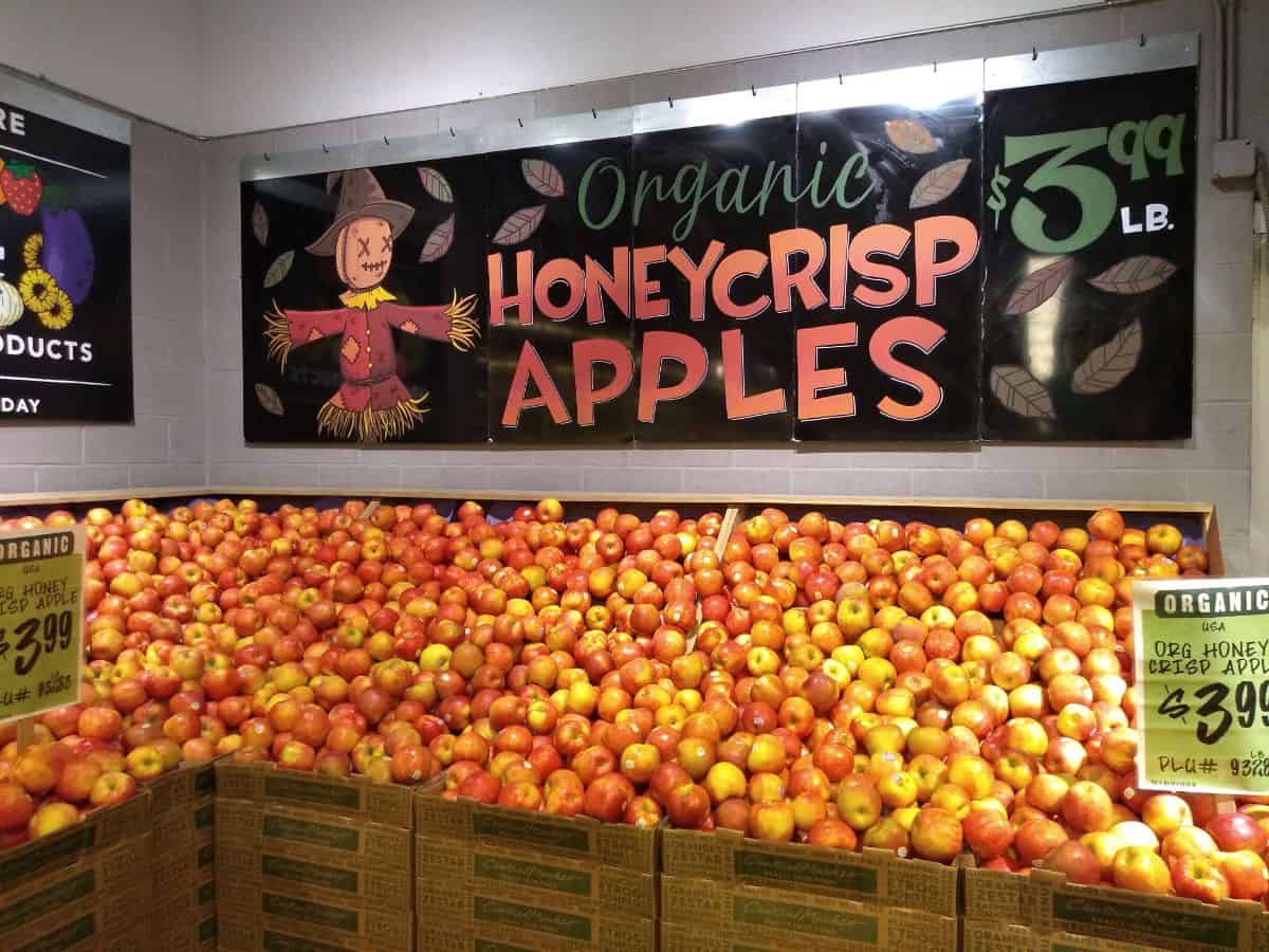 A grocery store display of Organic Honeycrisp apples stacked up high.