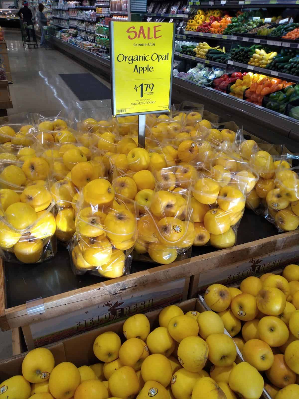 A display of Organic Opal apples on sale for $1.79/lb. The apples are in plastic bags.