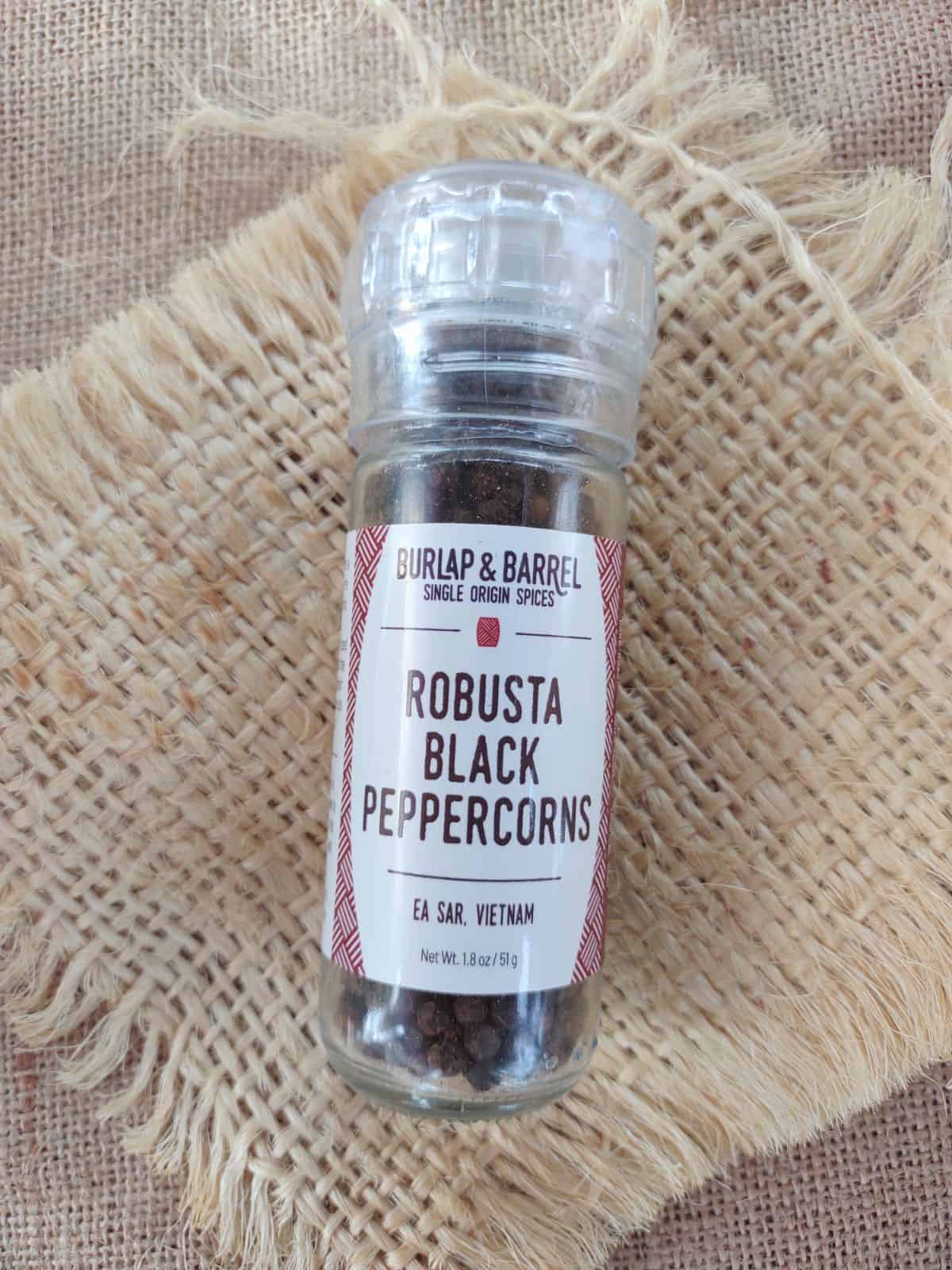 Burlap & Barrel Robusta Black Peppercorns on a piece of burlap