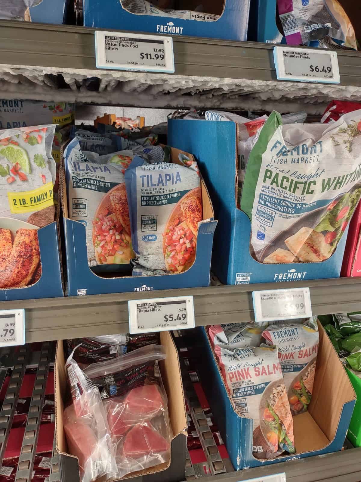 Bags of different types of frozen fish in the freezer section at an ALDI store.