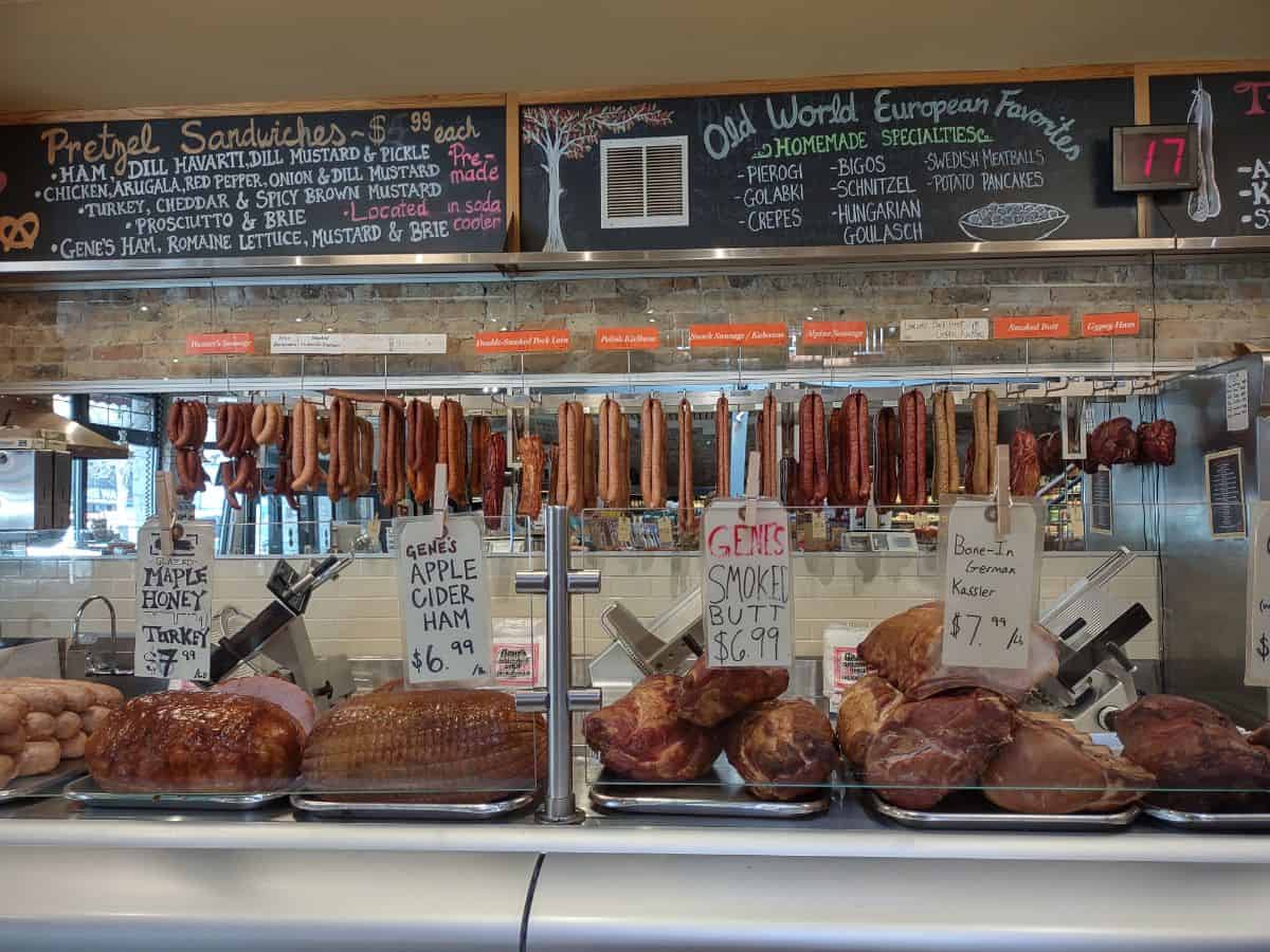 Gene's Sausage Shop in Chicago is pictured showing deli turkey and ham with sausages hanging up in the background.