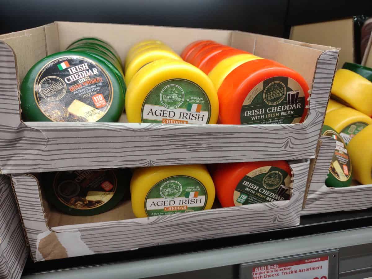 Boxes of green, yellow, and orange waxed cheddar cheeses on display at ALDI.