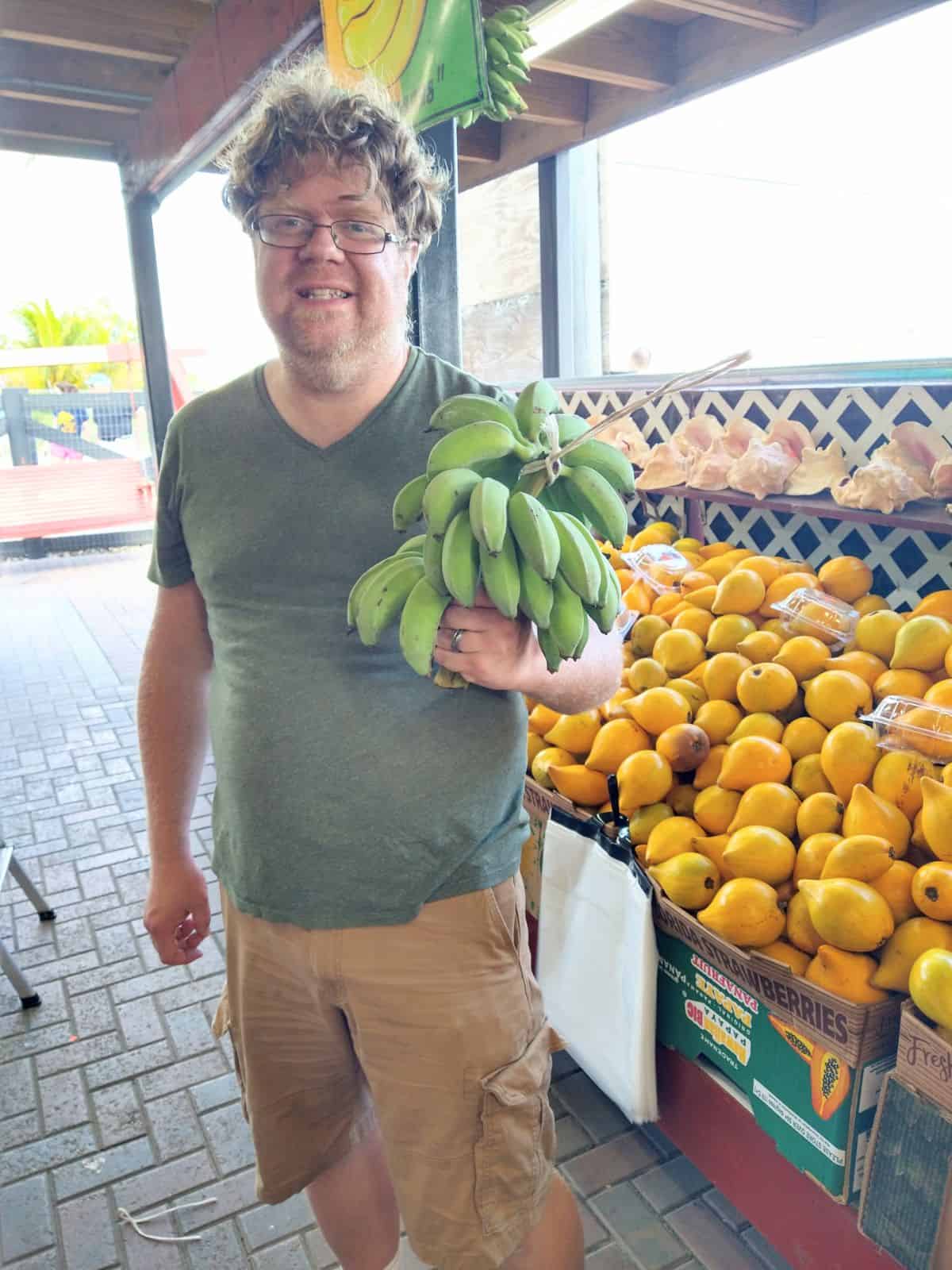 Eric Samuelson holding a bunch of green Mysore bananas at Robert is Here Produce in Homestead, Florida.