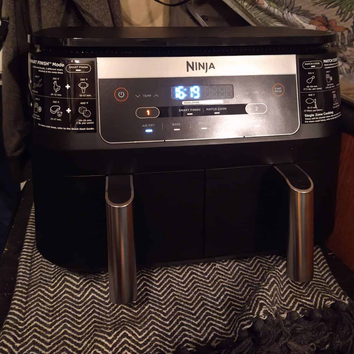 A black Ninja dual basket air fryer set to air fryer with 16 minutes and 19 seconds showing on the clock.