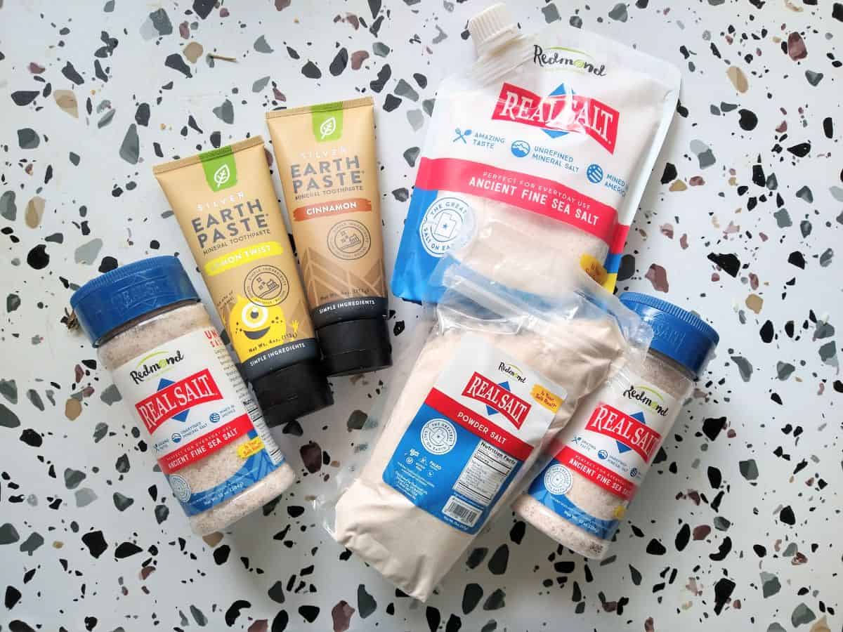 Different types of Redmond Real Salt products in different sized bags and shakers along with Redmond Earth Paste toothpaste tubs.