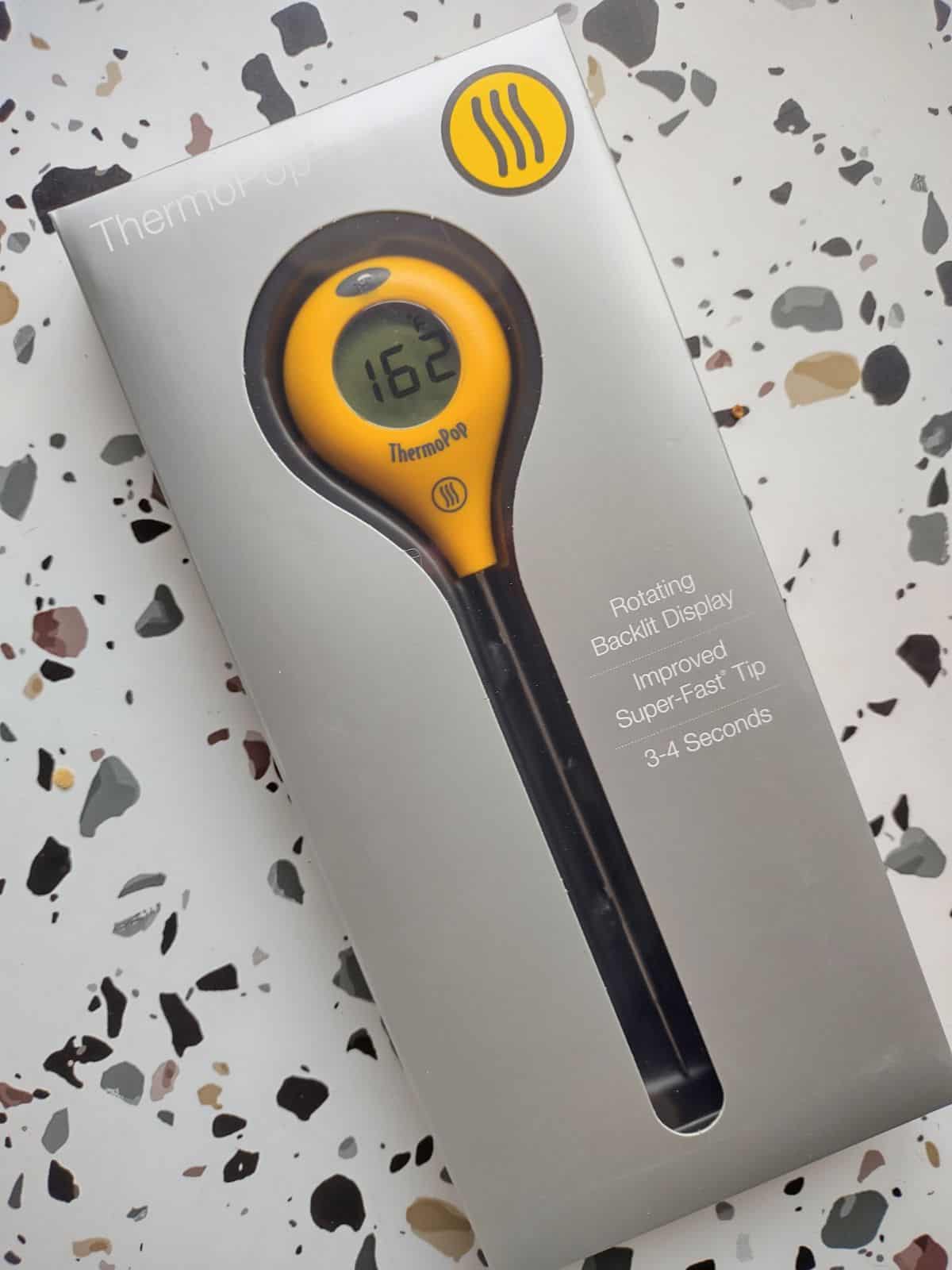 A yellow ThermoWorks ThermoPop thermometer inside a gray box.
