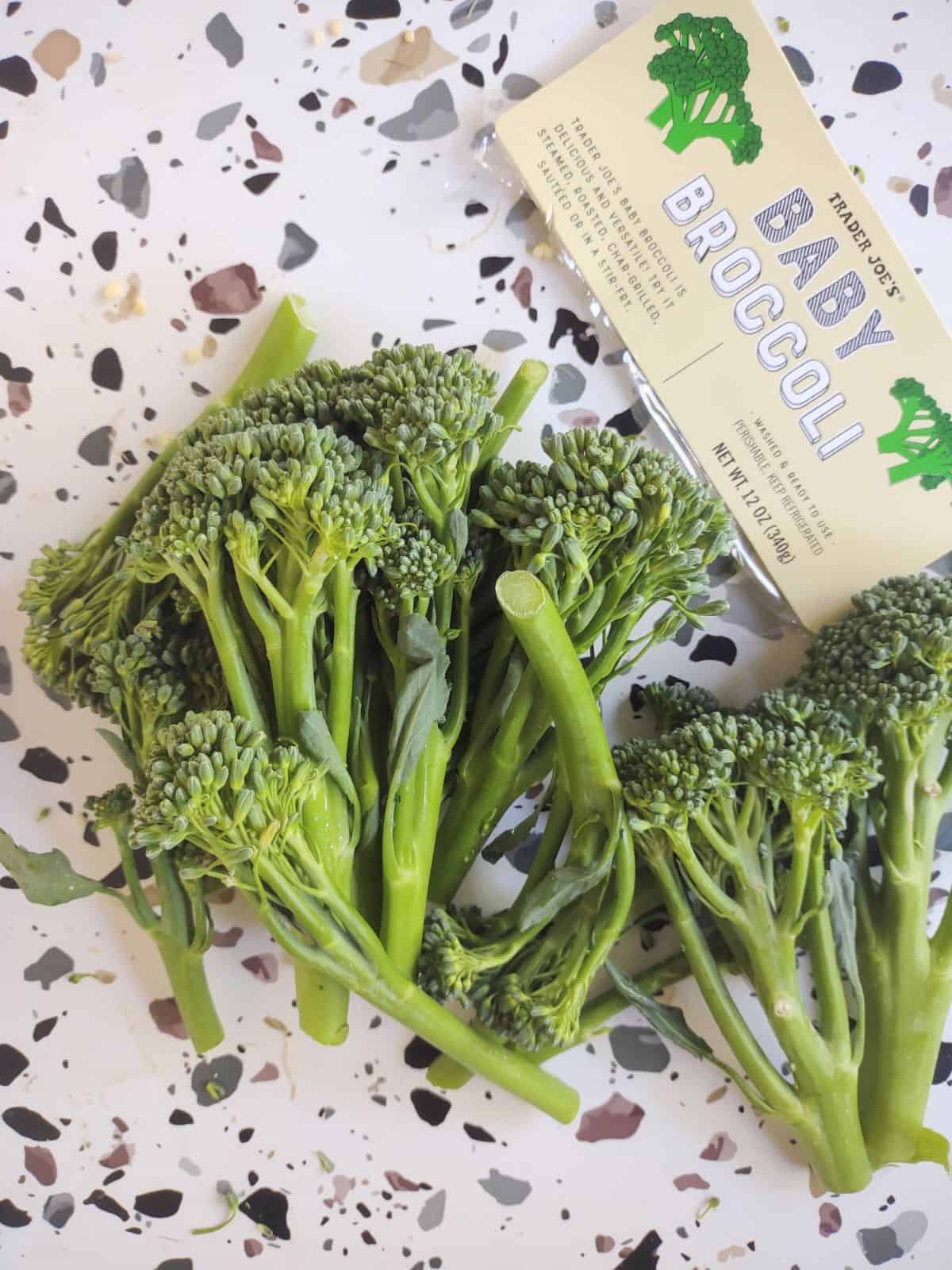 Baby broccoli from Trader Joe's sitting on a white table with spots.