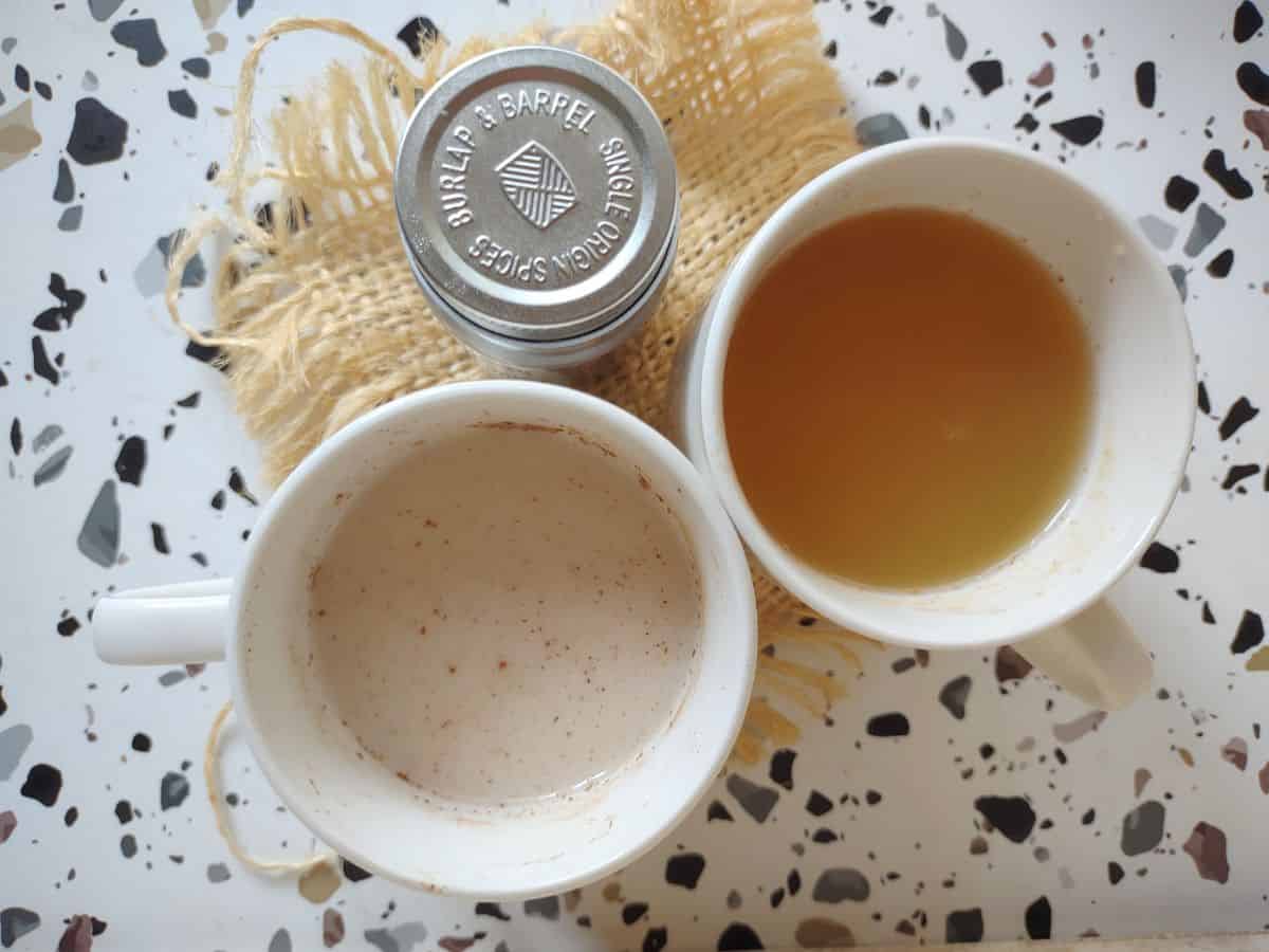 Two cups of cinnamon tea. The whitish colored tea has milk in it, and the one with the organish hue has orange juice in it. 