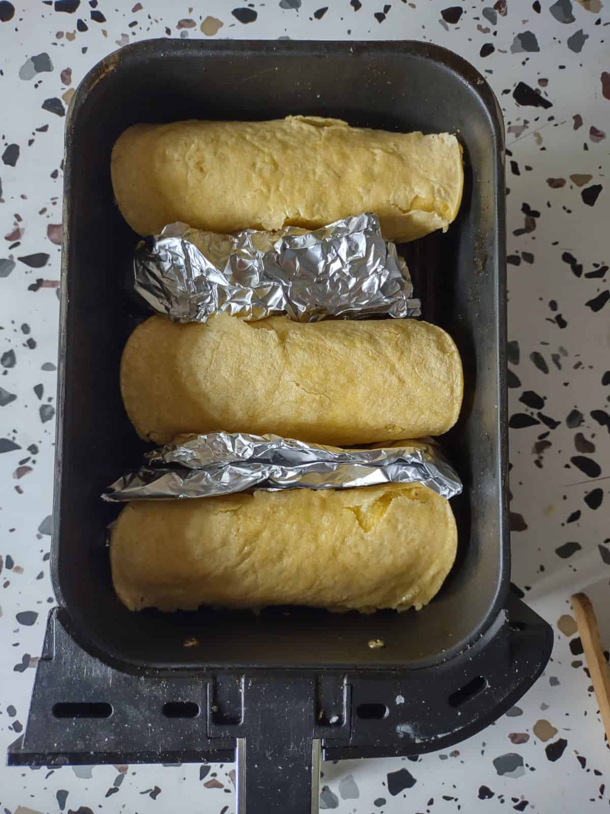 Corn tortilla that are stuffed with foil and turned upside down and placed in an air fryer basket with some foil wedges between the tortillas. 