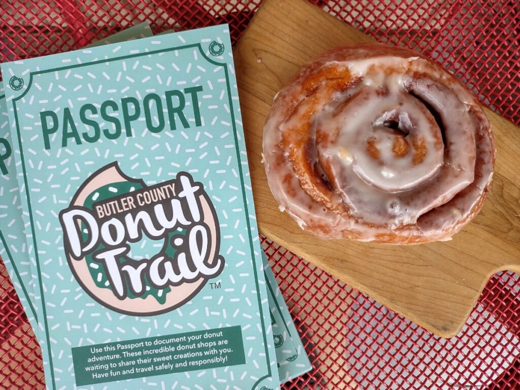 A cinnamon roll on a red metal table with a donut trail passport.