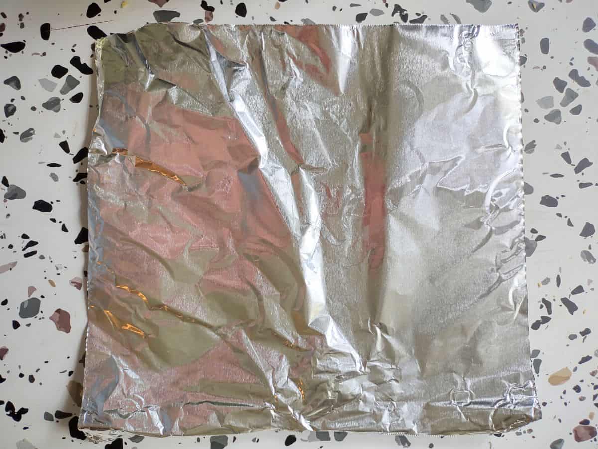 A square piece of heavy duty aluminum foil on a table.