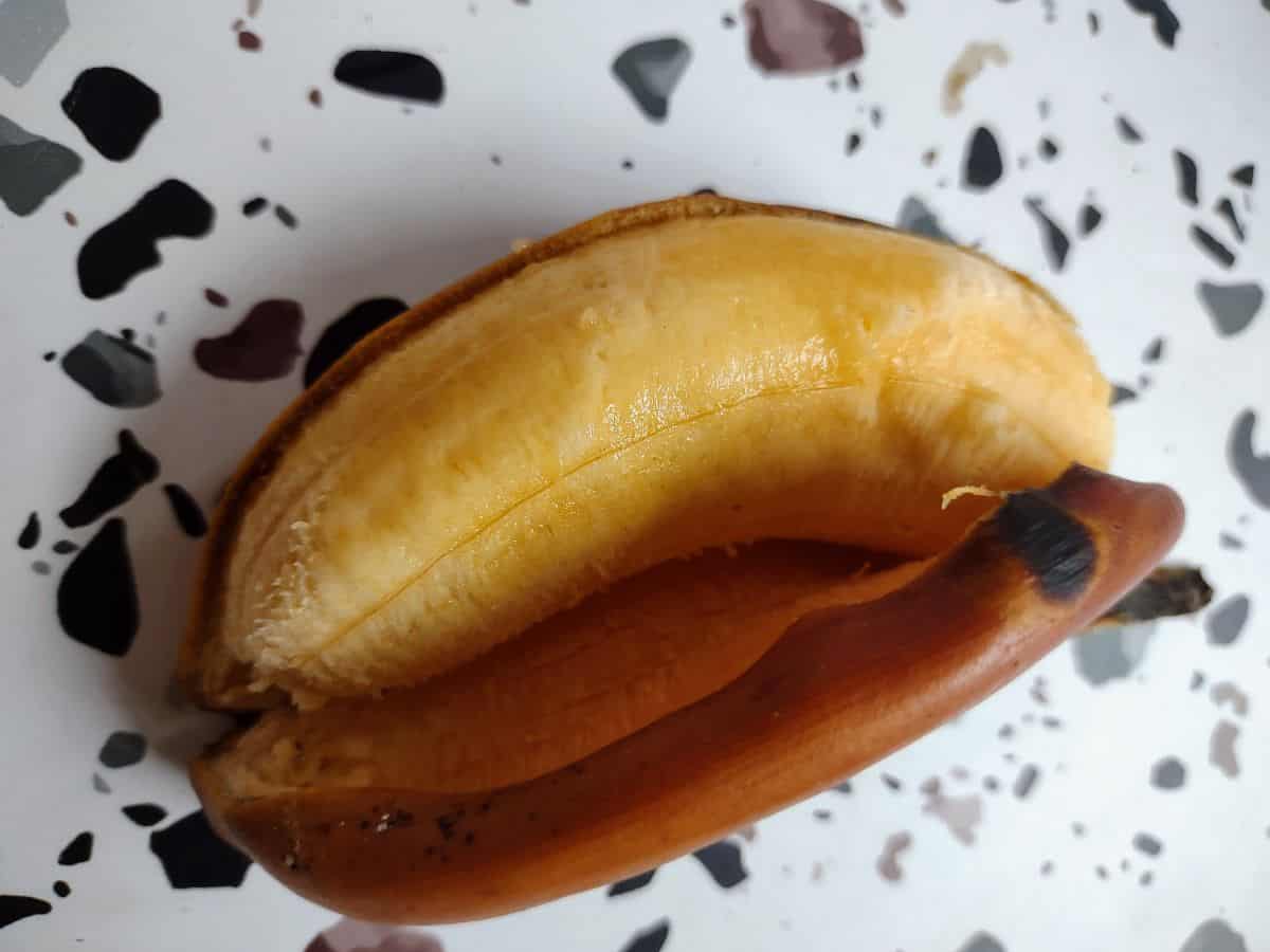 An opened up red banana sitting on top if it's peel.