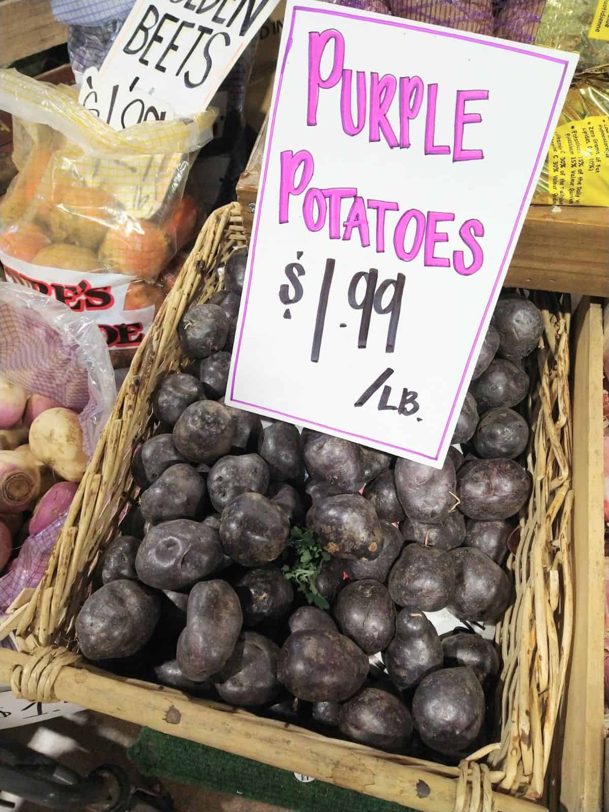 Purple potatoes in basket with a sign saying they are $1.99 a pound.