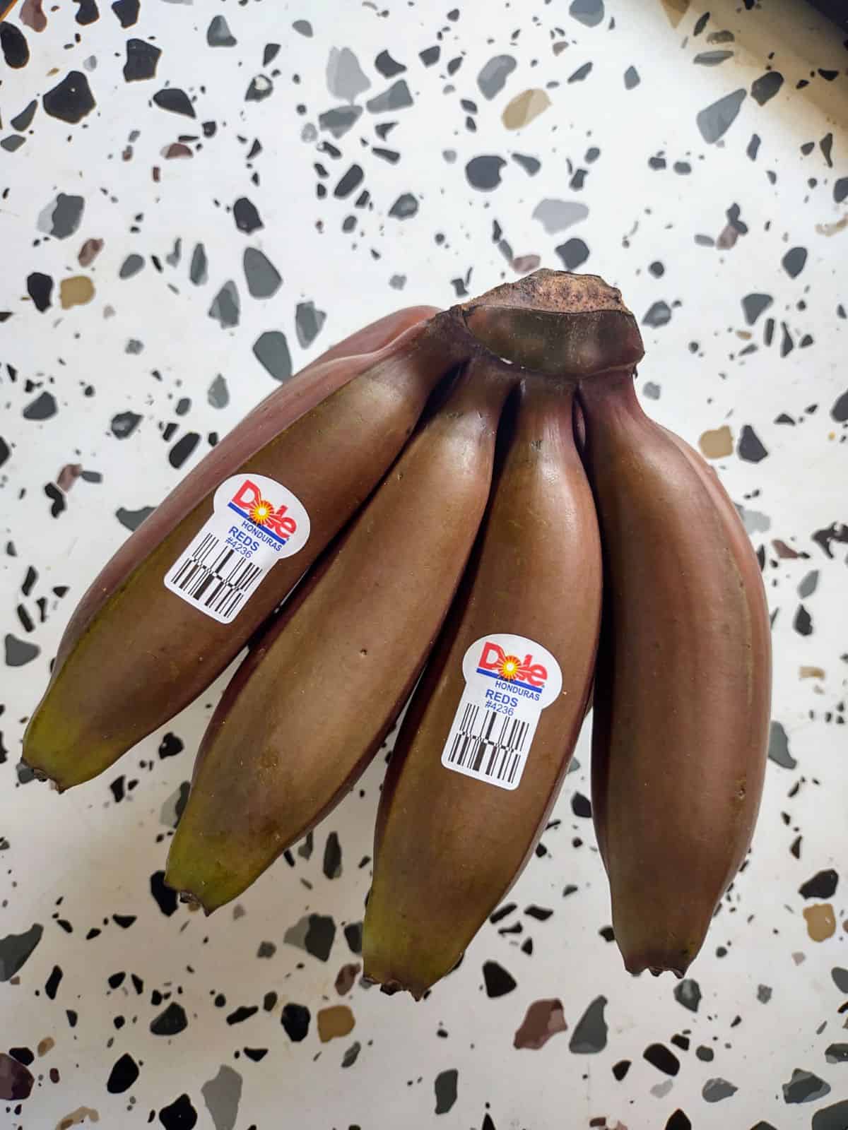 A bunch of red bananas that are unripe.