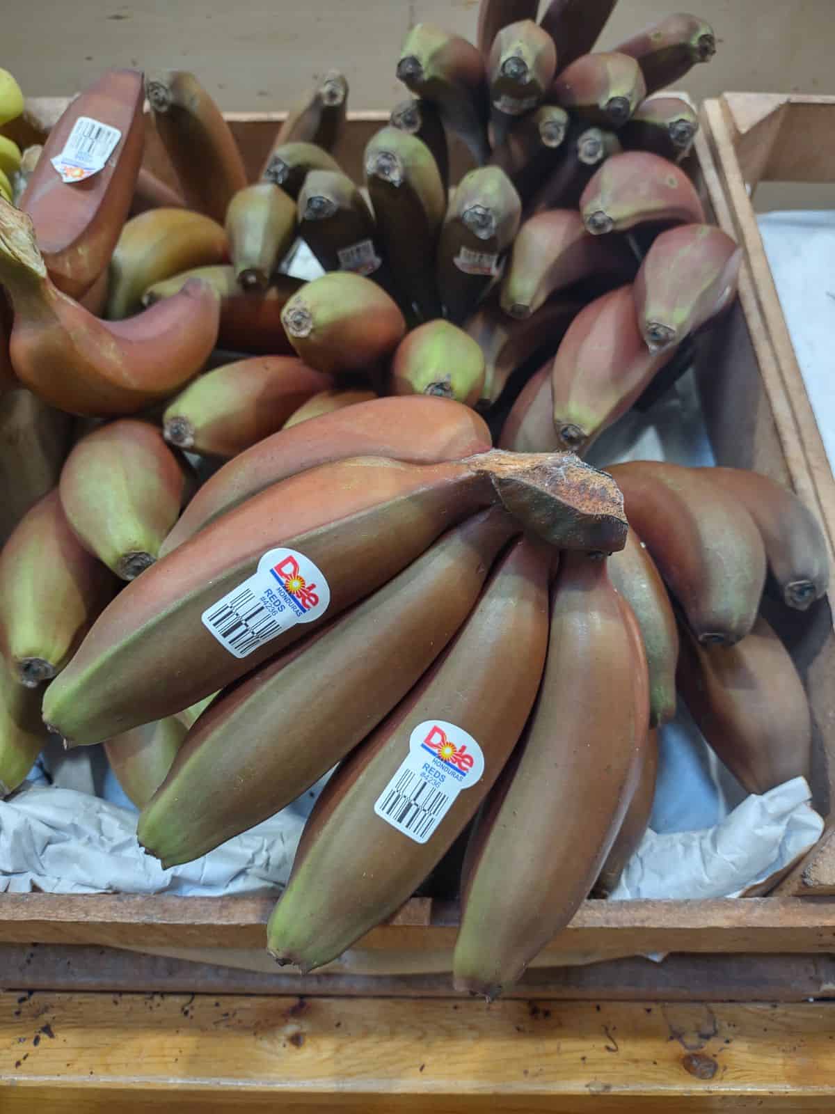 Bunches of Dole red banana on display at a grocery store.