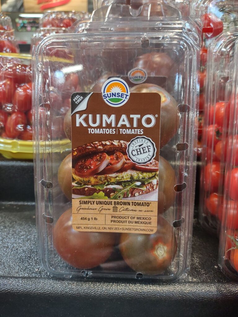 A clear plastic container of Sunset Kumato Black Tomatoes.