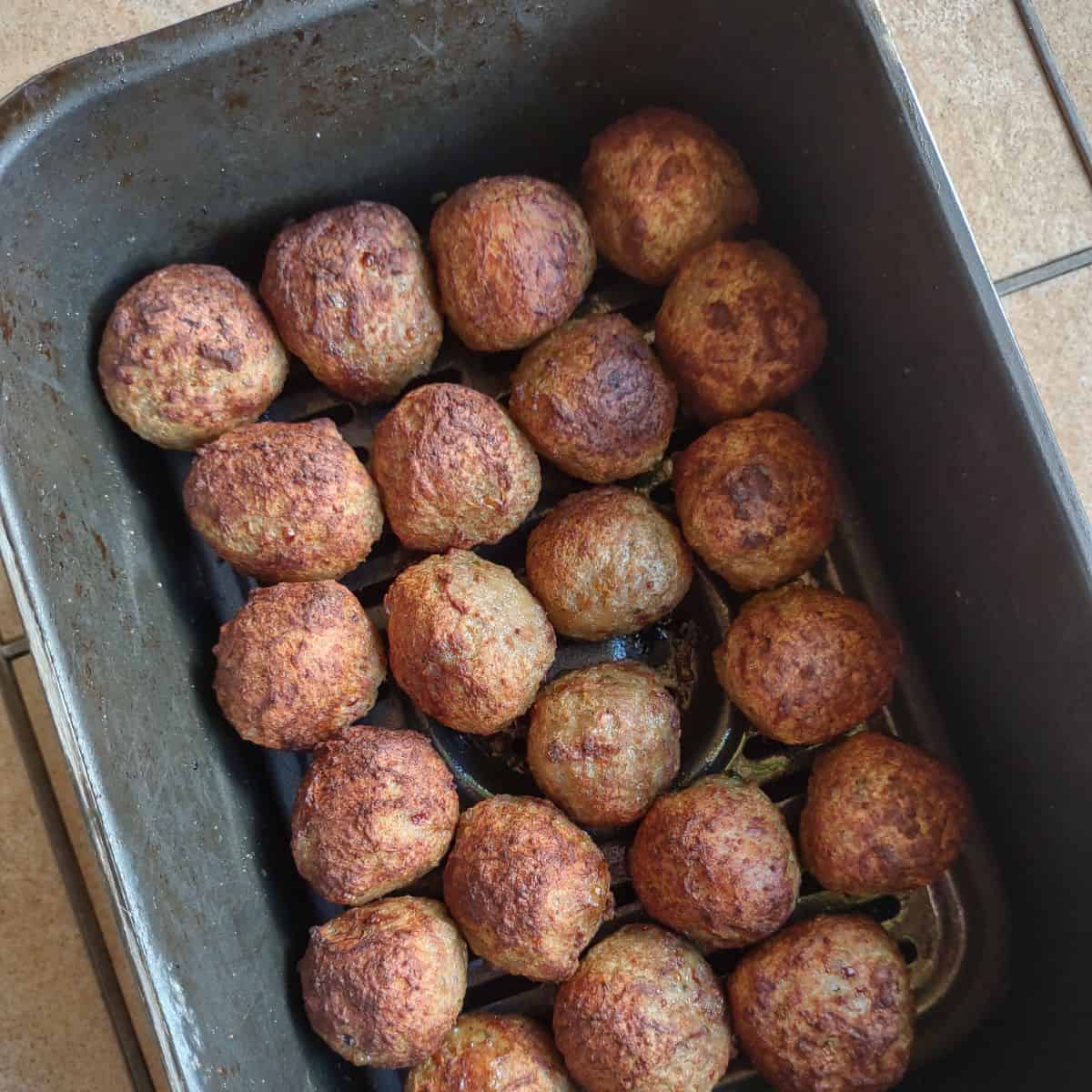 Browned Kirkland meatballs in a black air fryer basket.