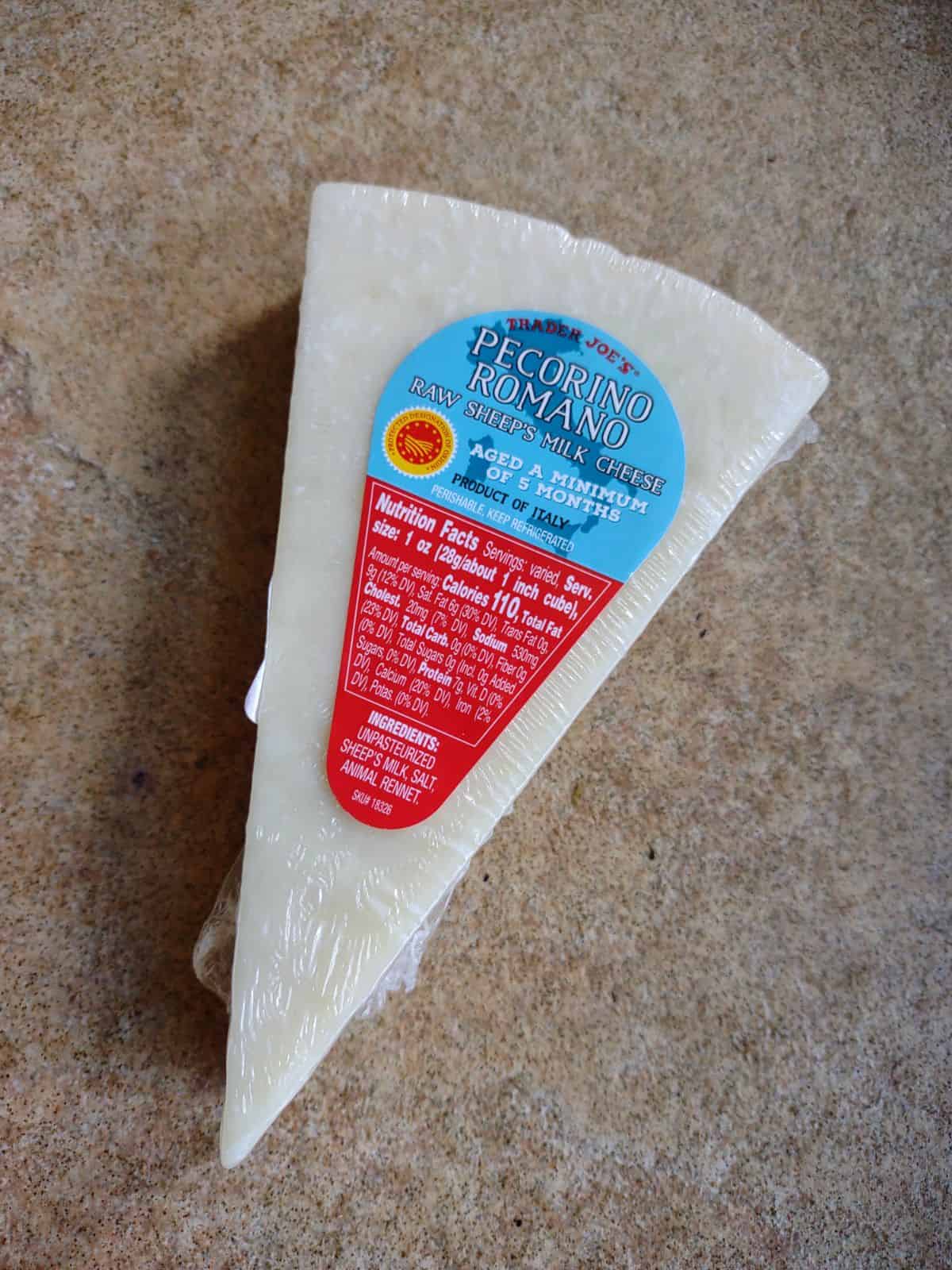 A wedge of Pecorino Romano cheese from Trader Joe's on a brown tile table.