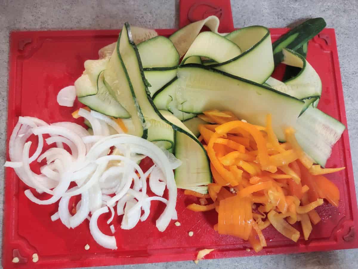 Onions, zucchini strips, and blue peppers prepared for lasagna.